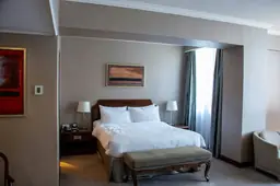 Elegant Hampton Inn & Suites Raleigh Downtown guest room with a plush king-sized bed, wall-mounted artwork, and natural light from window.