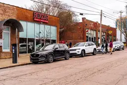 Exterior view of Boxcar Bar + Arcade with patrons and parked cars along the street.