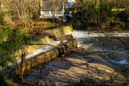 Sunlight over Lassiter Mill Historic Park with cascading waterfall and surrounding greenery.