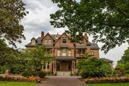 North Carolina Executive Mansion with lush gardens and surrounding greenery under a cloudy sky.