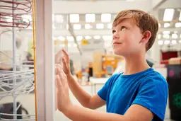 Young boy in blue shirt engaging with an interactive exhibit at Marbles Kids Museum.
