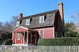Joel Lane Museum House with yellow exterior, red shutters, and colonial architecture under a clear blue sky.