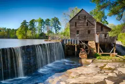 Old wooden mill with waterwheel and waterfall at Historic Yates Mill County Park.
