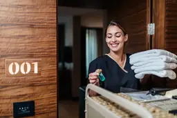 Housekeeper smiling while stocking room 001 with towels and toiletries at The Inn on Pamlico Sound.