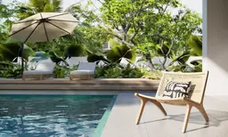 Tranquil poolside lounging area with wooden chair and sun umbrella at Ocean Reef Resort, surrounded by lush greenery.