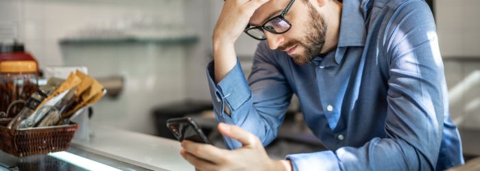 SMB owner looking on his phone with desperation struggling with communication issues