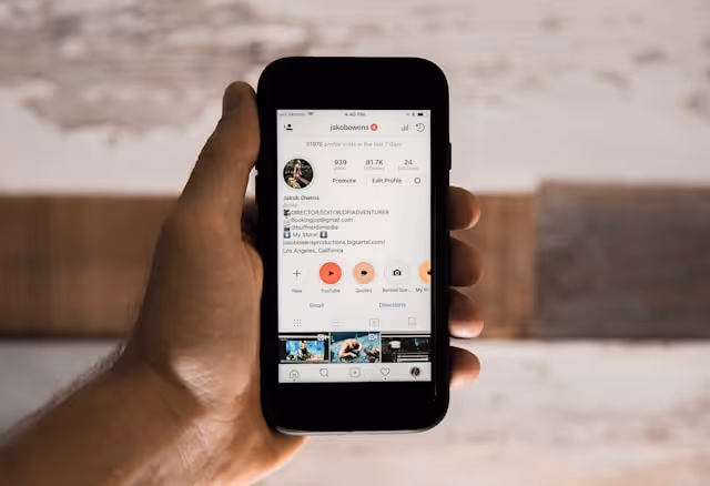 hand with mobile phone showing a social media profile