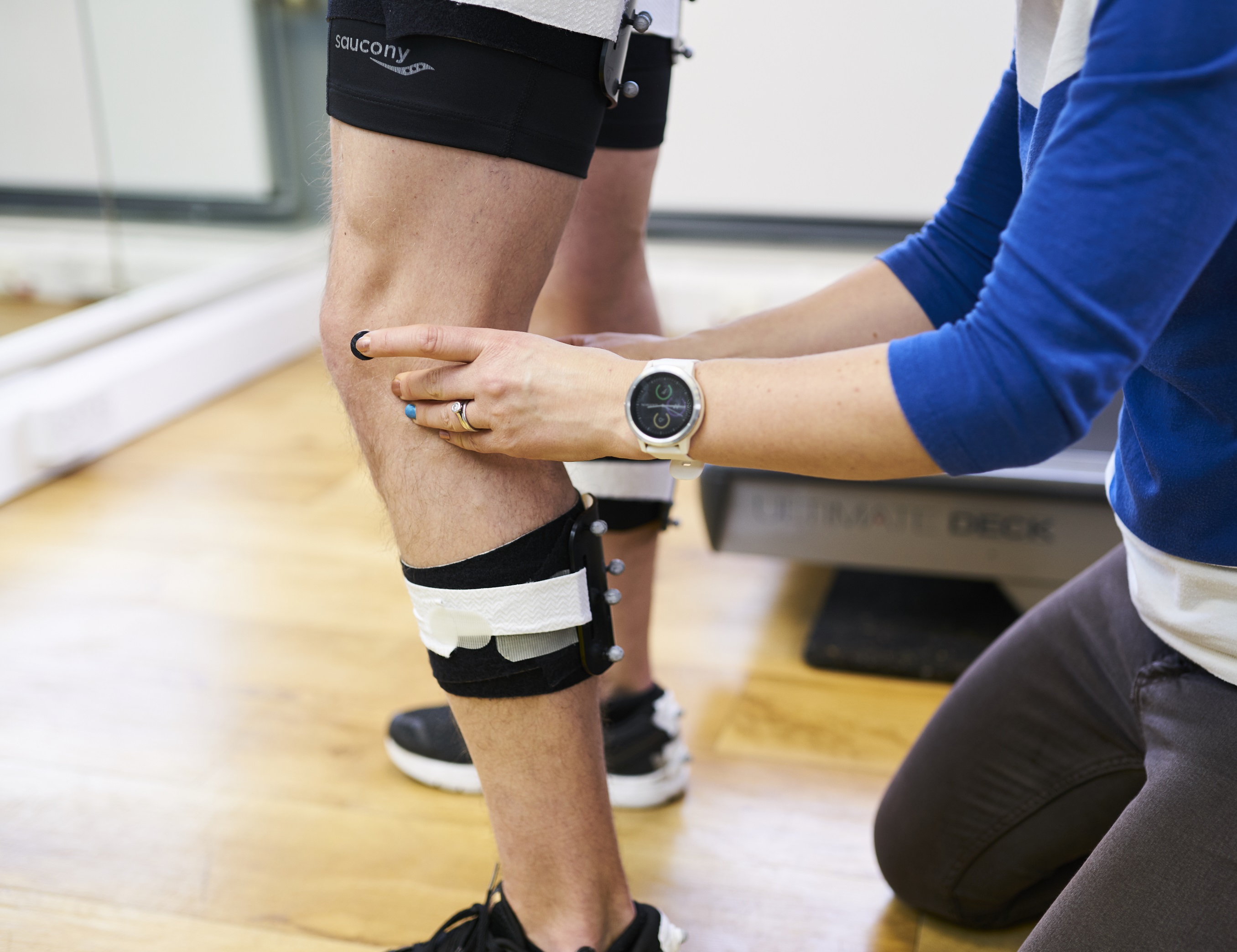 A clinician places reflective markers on a patient's knee.