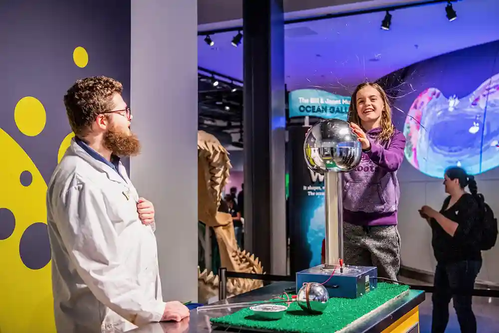 A visitor at the Discovery Centre smiles as her hair reacts to static electricity.