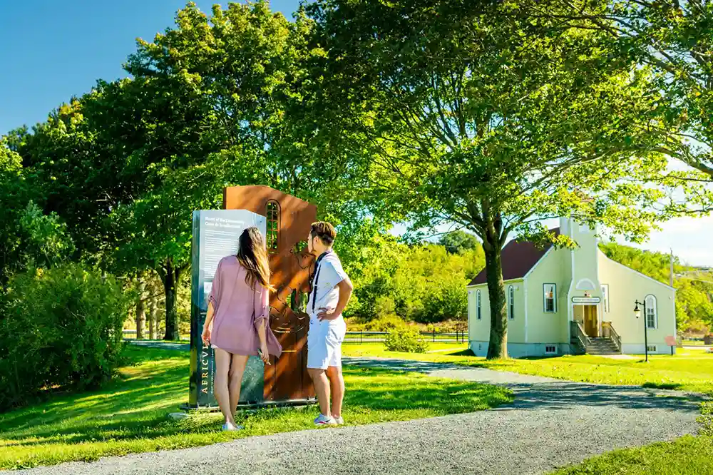 Two guests of The Africville Museum read an interpretive panel located just steps from the museum, which is off to the distance to the right.