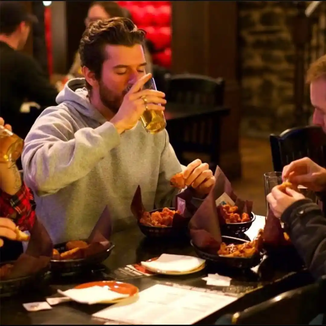 A person enjoys a beverage while dining at Auction House in Halifax.