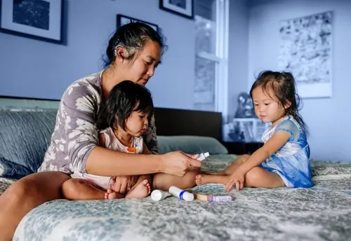 Mother playing with her two children on a bed.