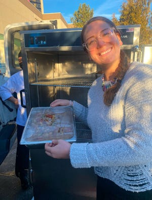 An Eddy House worker shows a tray of leftover food from the Atlantis casino's buffet that will be delivered to the nonprofit for at-risk youth.