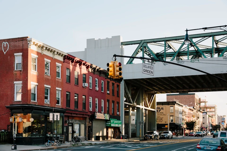 Gowanus Neighbourhood in Brooklyn, New York - Urban street scene with red brick buildings, bicycles, traffic light, and an overhead green metal bridge.