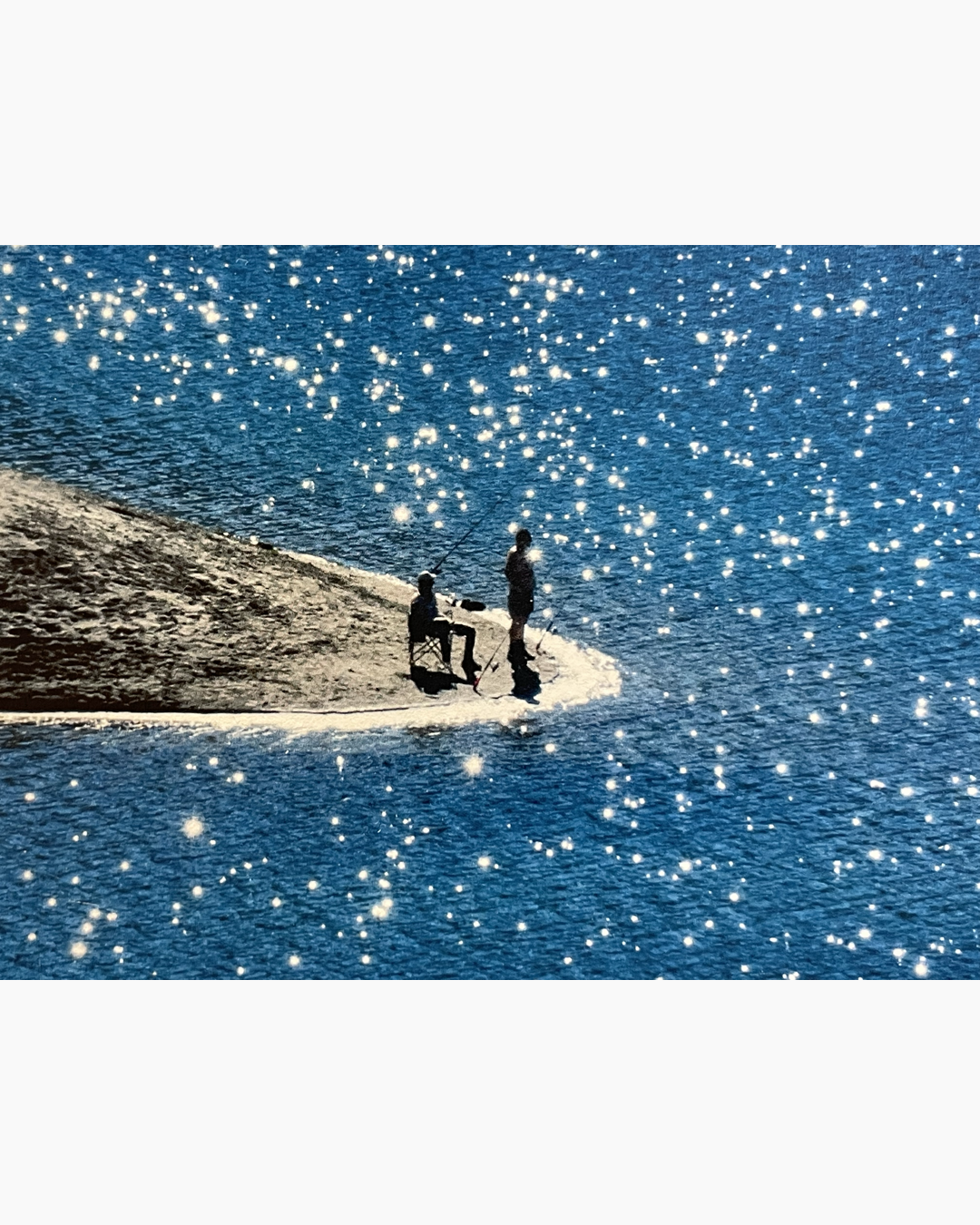 두 사람이 물가 모래사장 끝에 앉아 낚시를 하고 있으며, 반짝이는 햇빛이 푸른 바다 위에 반사되고 있다.