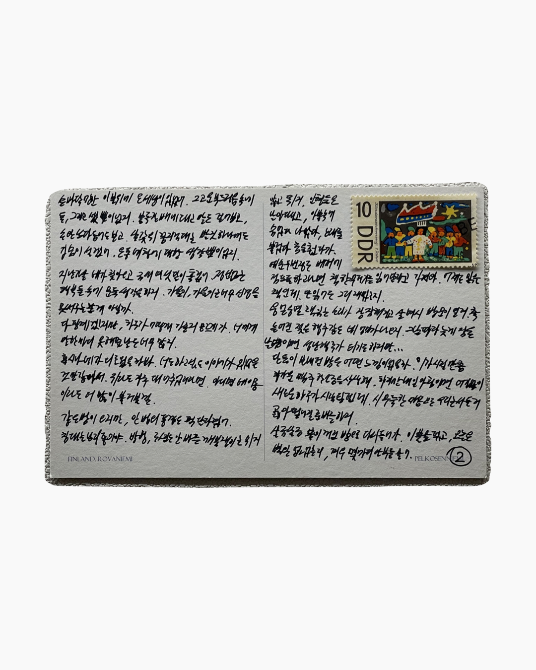 손글씨로 가득 채워진 엽서 뒷면, 오른쪽 상단에 다양한 인물과 색상으로 구성된 우표가 붙어 있음.