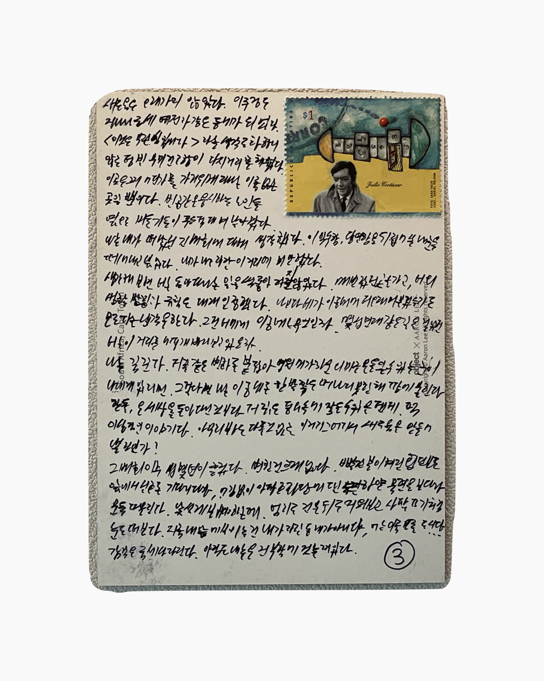 한국어로 손글씨로 작성된 긴 편지 위에 줄무늬 배경과 Julio Cortázar 이름과 초상화가 있는 우표가 부착된 이미지.