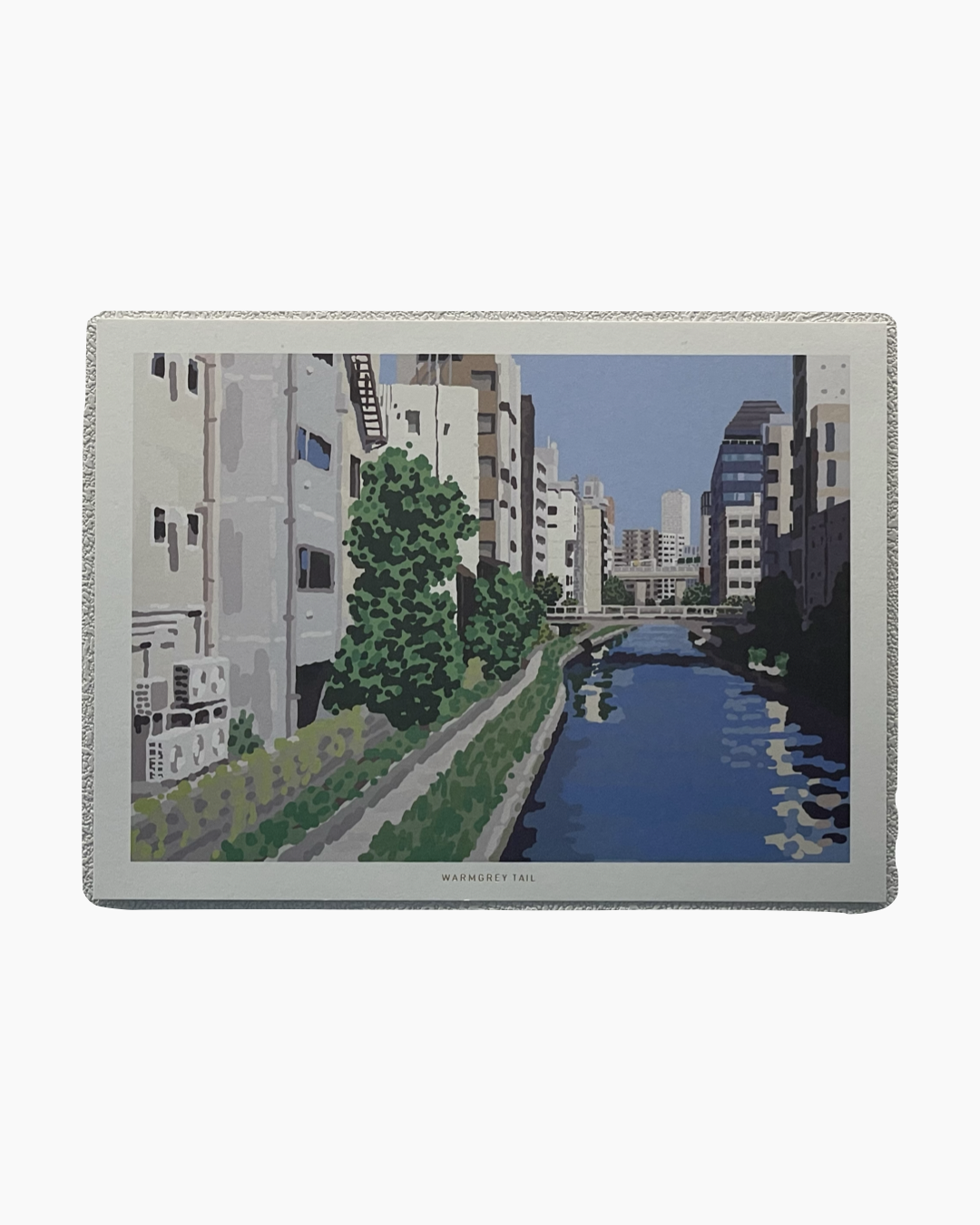 도시의 강변을 따라 늘어선 건물들과 푸른 나무들, 그리고 강에 비친 하늘과 건물들의 모습.