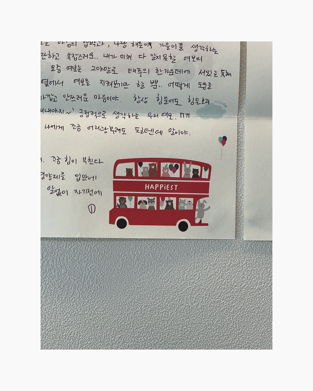 빨간 이층버스에 동물 캐릭터들이 타고 있고, 버스 위에 HAPPIEST라는 글자가 적혀 있는 편지 한 장.