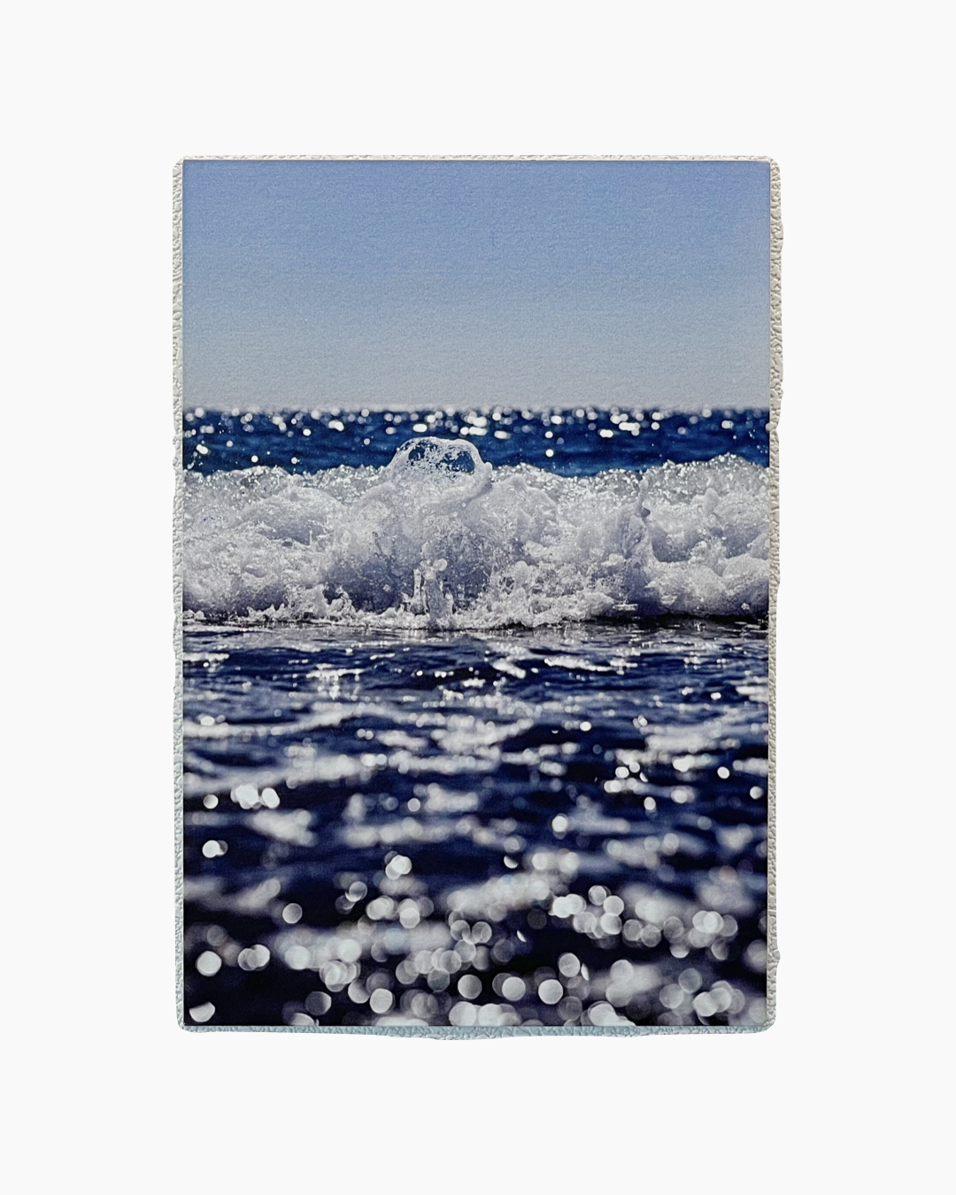 태양빛에 반짝이는 파도가 부서지는 바다 풍경.