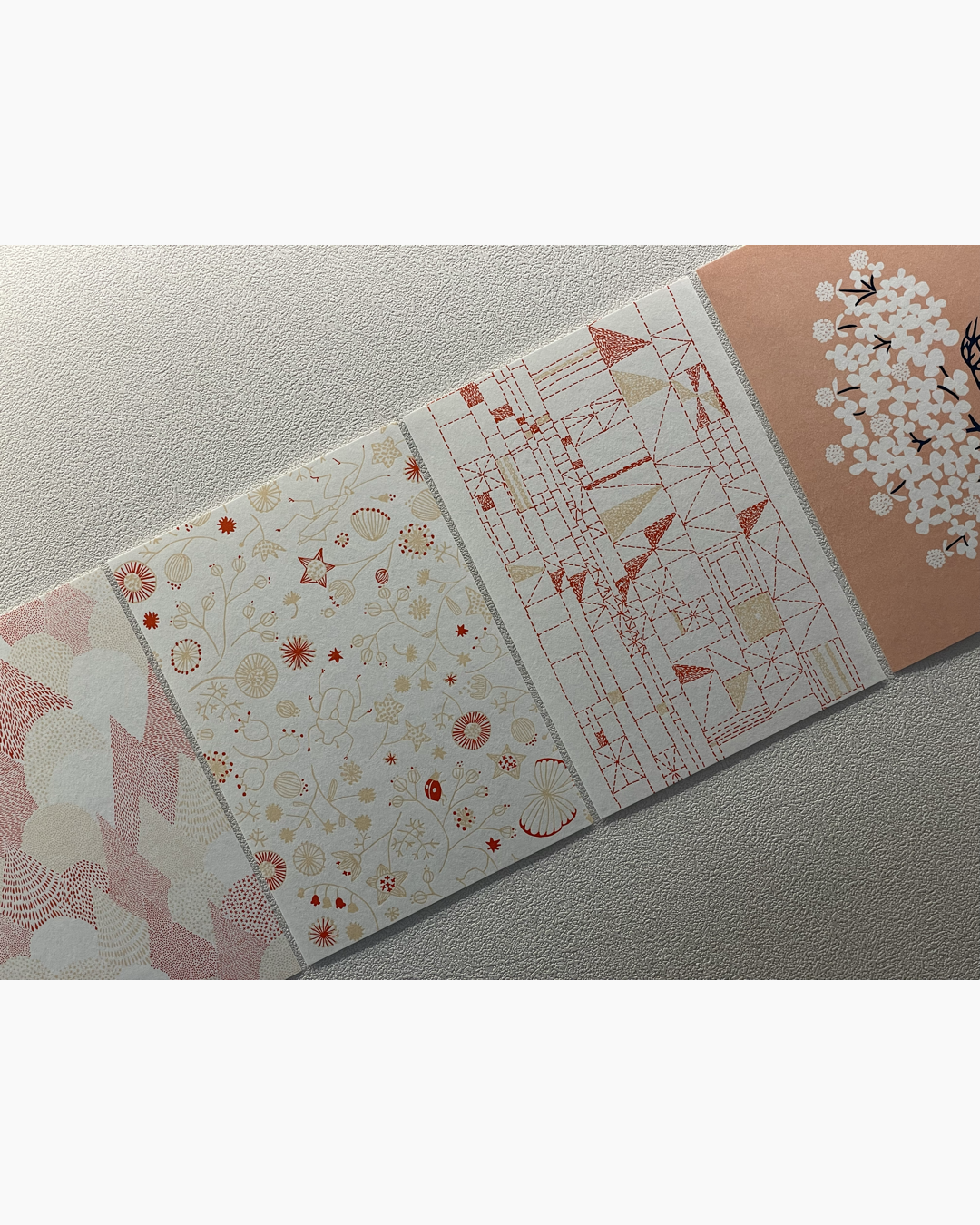 옅은 분홍색, 빨간색, 베이지색 패턴이 각각 다른 네 개의 직사각형 카드가 나란히 놓여 있음.