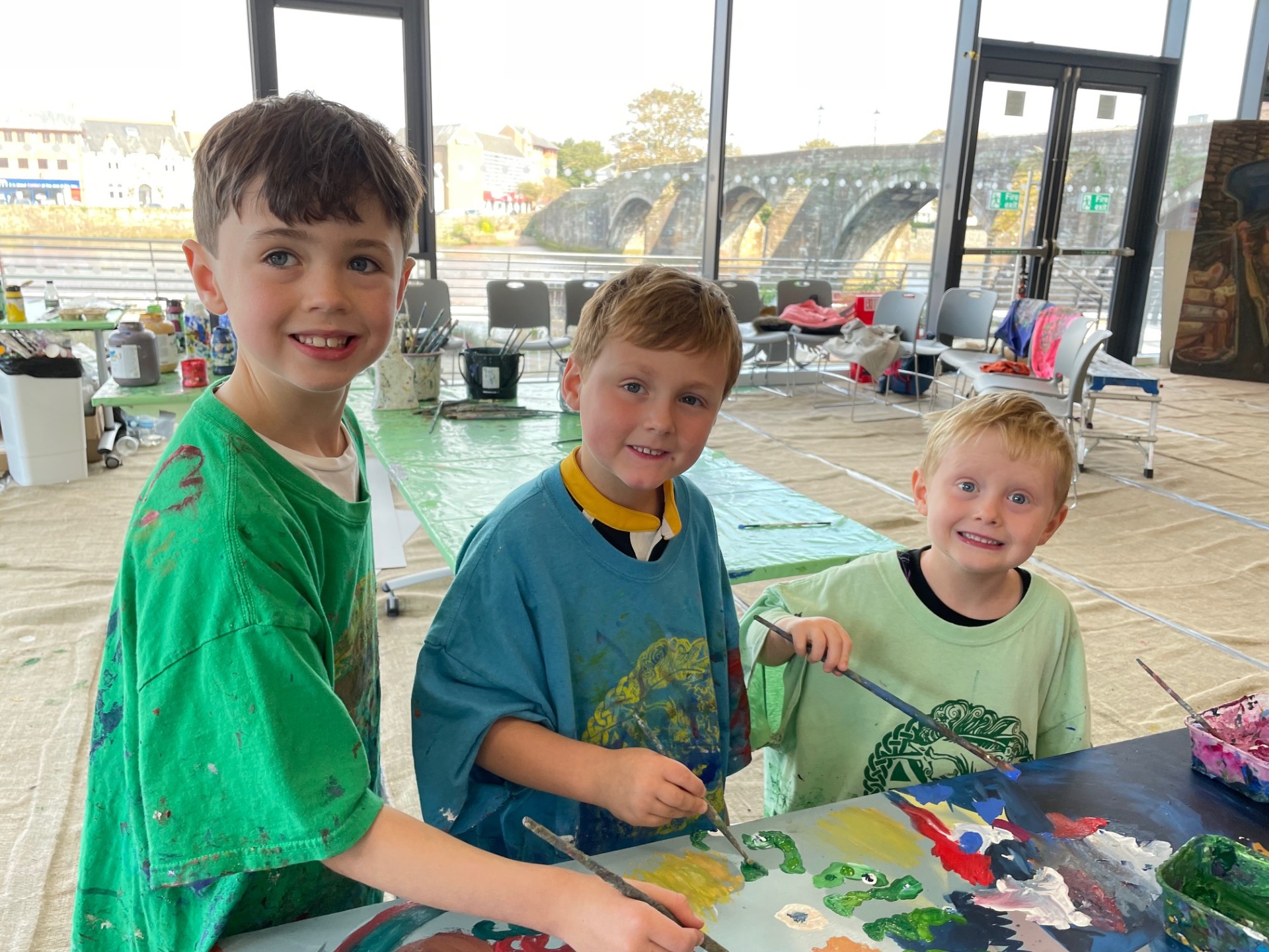 Three young boys painting a picture for the mural