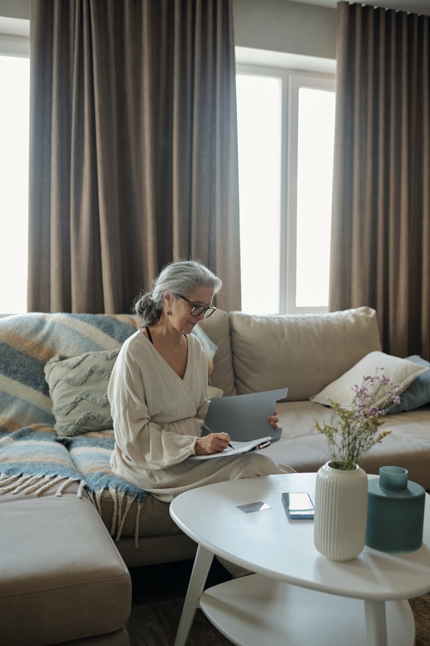 elderly lady sitting on a couch filling in paper work