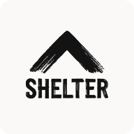 Man with beard in a blue suit and white shirt sitting at a table with clasped hands.