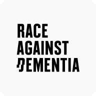 Man with beard in a blue suit and white shirt sitting at a table with clasped hands.