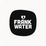 Man with beard in a blue suit and white shirt sitting at a table with clasped hands.