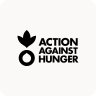 Man with beard in a blue suit and white shirt sitting at a table with clasped hands.