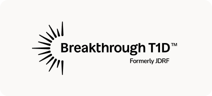 Man with beard in a blue suit and white shirt sitting at a table with clasped hands.