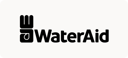 Man with beard in a blue suit and white shirt sitting at a table with clasped hands.