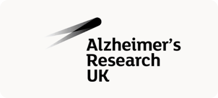 Man with beard in a blue suit and white shirt sitting at a table with clasped hands.