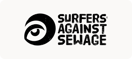 Man with beard in a blue suit and white shirt sitting at a table with clasped hands.