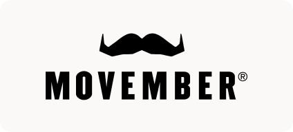 Man with beard in a blue suit and white shirt sitting at a table with clasped hands.