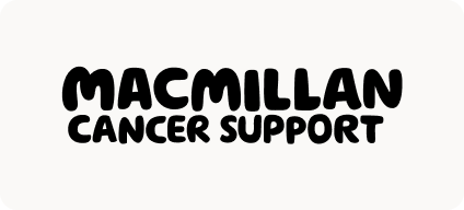 Man with beard in a blue suit and white shirt sitting at a table with clasped hands.