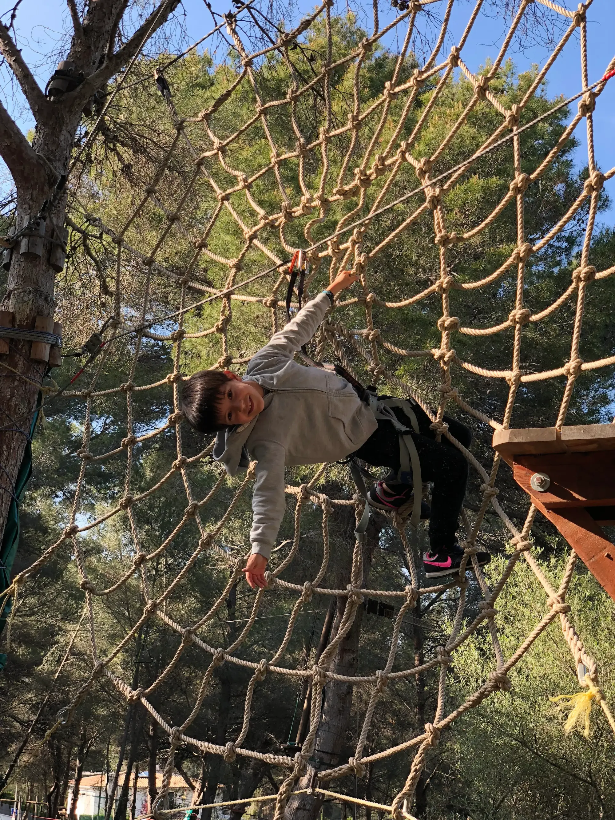 Child playing on a rope net in the forest at Jungle Parc in Santa Ponsa.