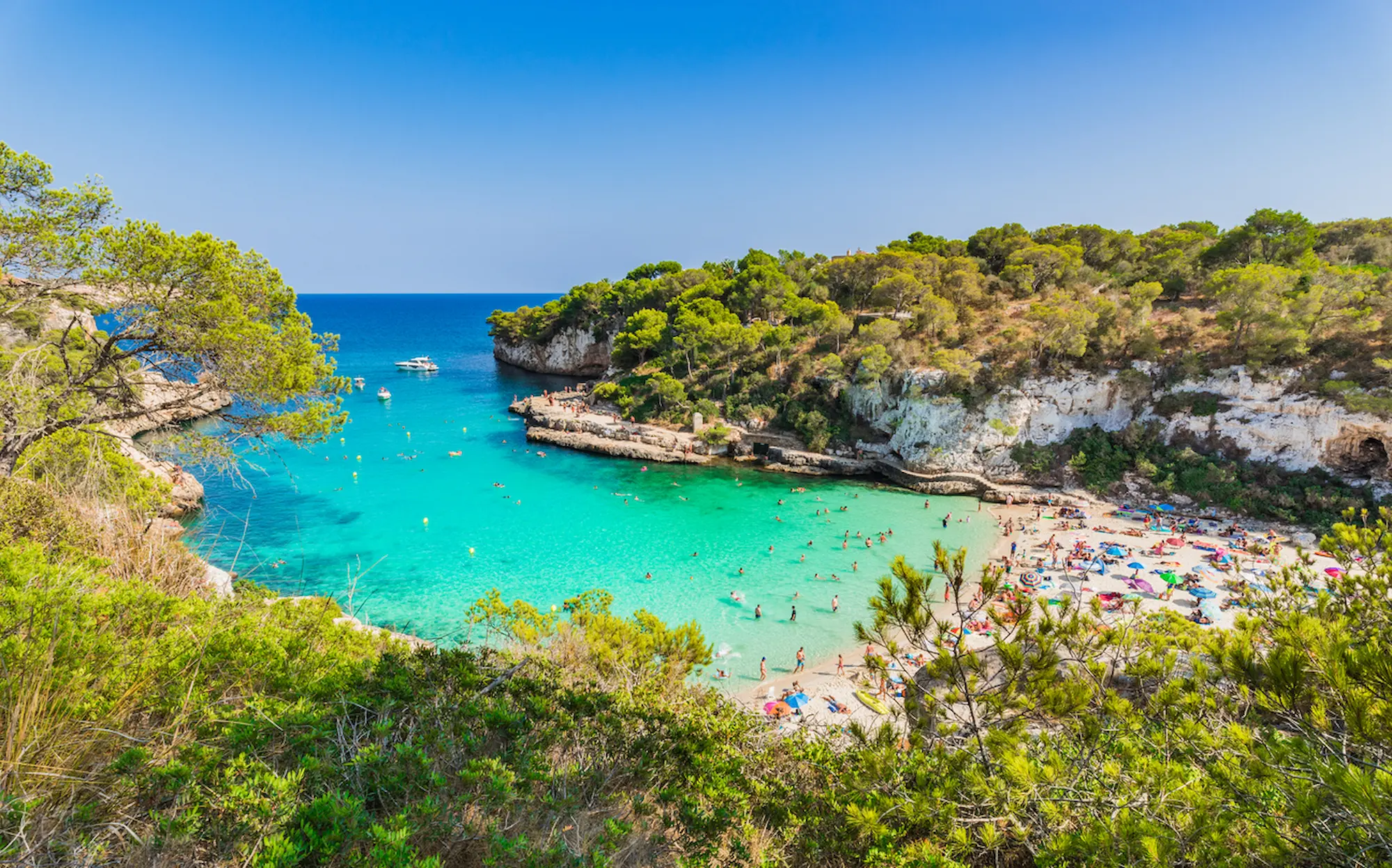 People on Cala Llombards surrounded by cliffs and trees