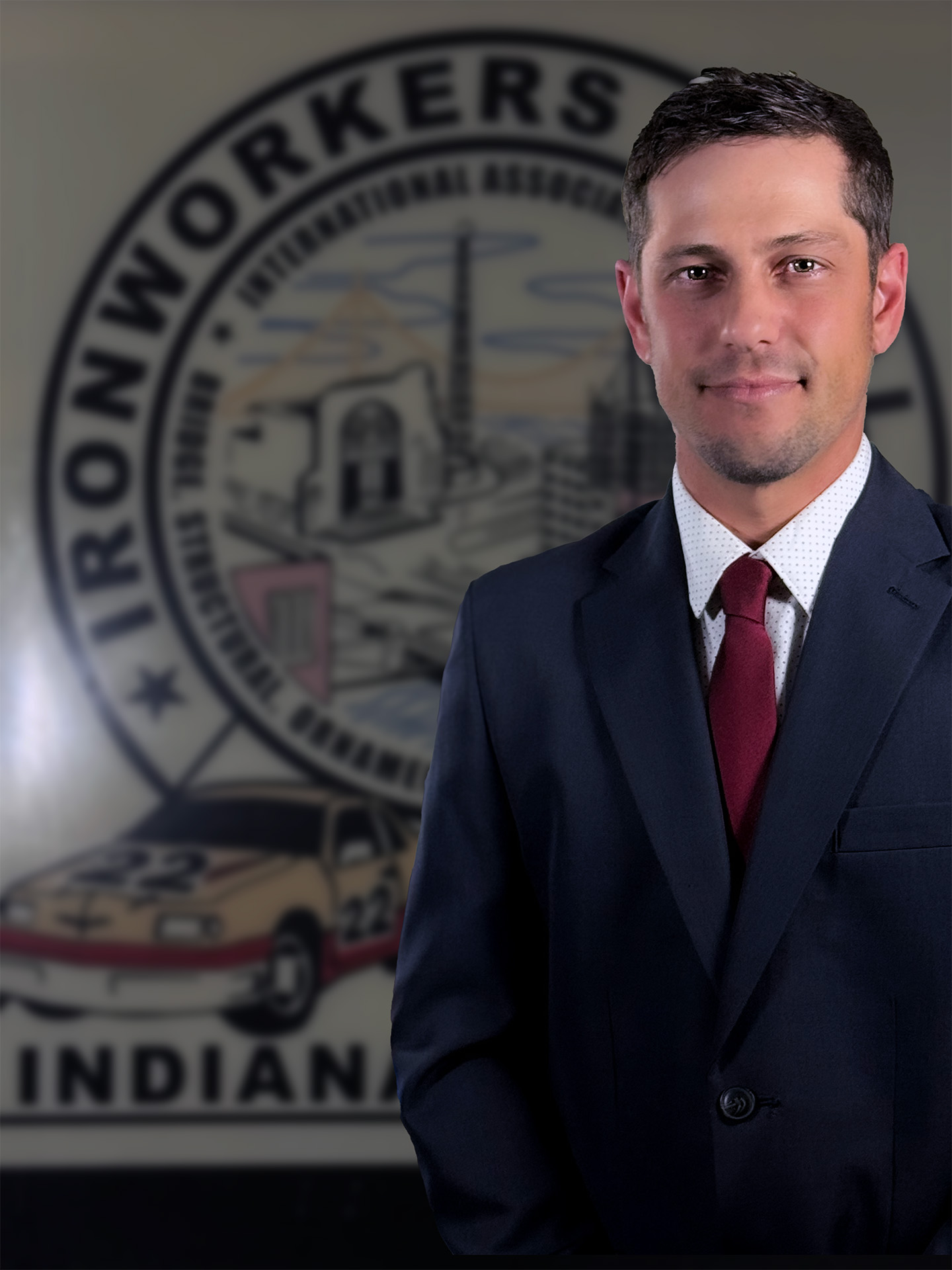 Ironworkers Local 22 President, Scott Hirtzel, wearing a dark blue suit and red tie standing in front of a blurred Iron Workers Indiana logo.