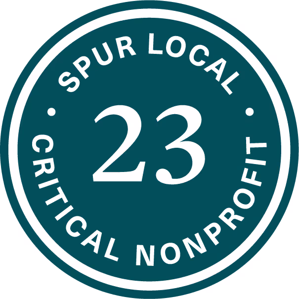 Circular dark teal seal with the white text 'SPUR LOCAL' above the number 23 and 'CRITICAL NONPROFIT' below it.