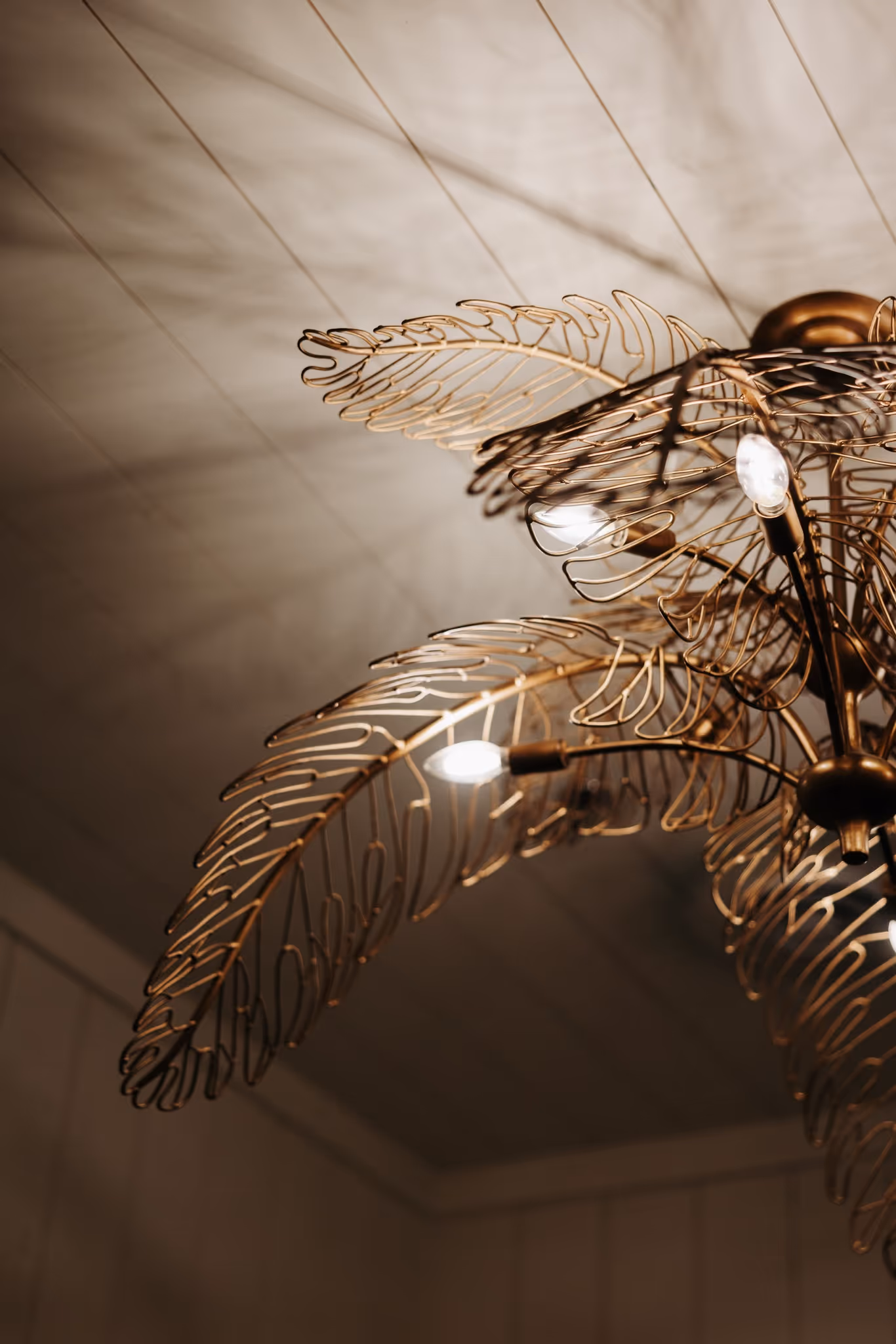 Decorative ceiling light fixture with gold metal leaf designs and small exposed bulbs.
