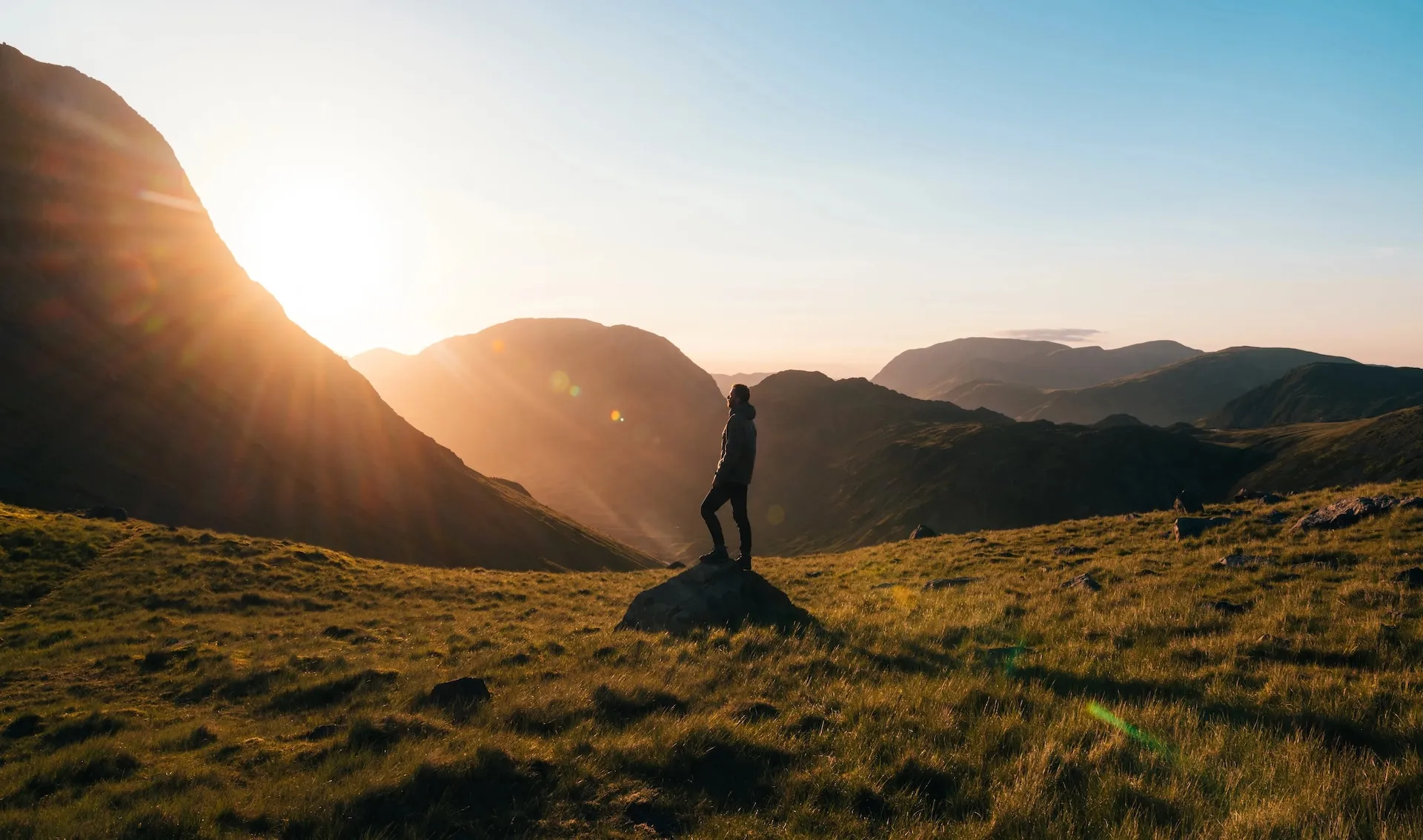 person hiking near mountains and sunset