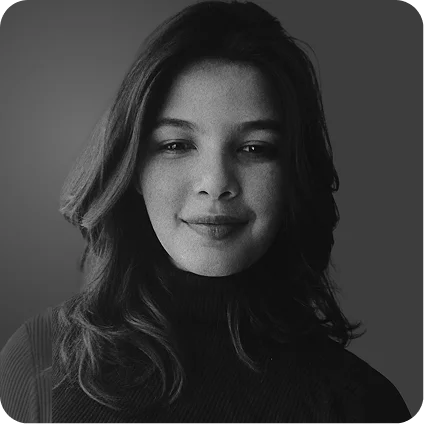 Black and white portrait of a woman with shoulder-length hair wearing a dark turtleneck, smiling softly.