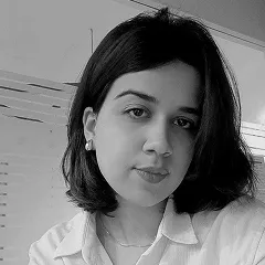 Black and white portrait of a woman with shoulder-length dark hair wearing a light-colored blouse and pearl earrings.