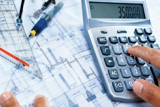 Contractor calculating construction project budget over architectural blueprints for FY24 legal compliance - Legalfinda
