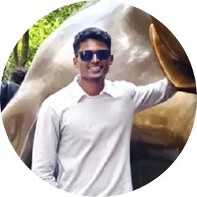 Man wearing sunglasses and a white long-sleeve shirt standing next to a golden sculpture of a bull.