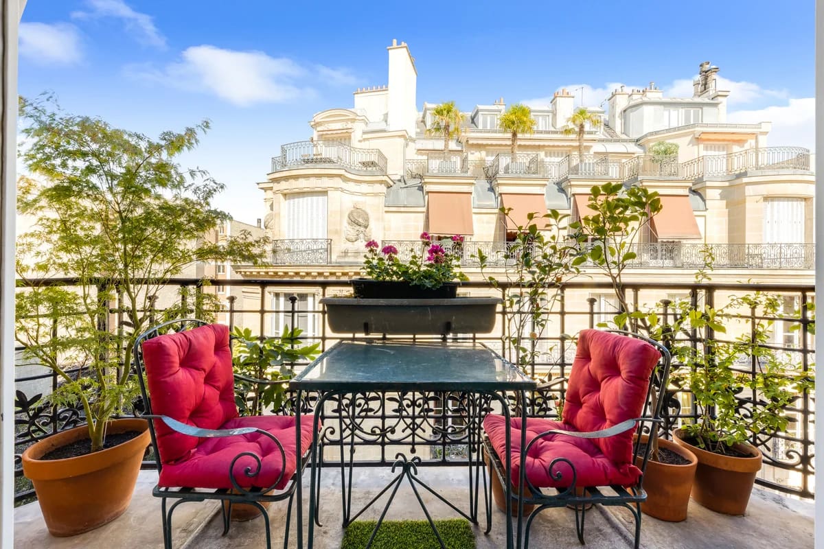 Une table et deux chaise sur le balcon d'un bel immeuble parisien