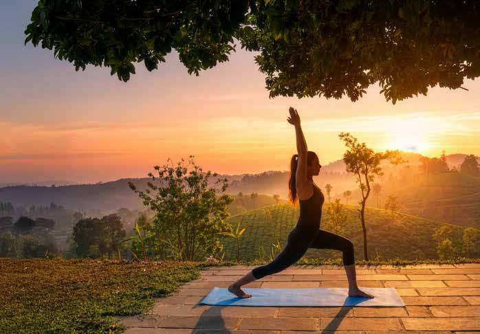 A guest practising yoga at sunrise overlooking the tea hills