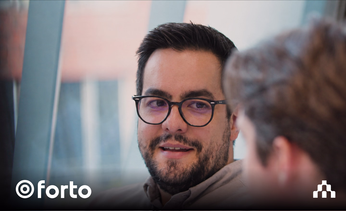Man smiling in conversation with a colleague, with the Forto logo overlay